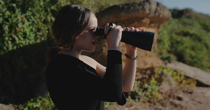 Woman tourist looking through binoculars at the nature, slow motion