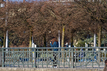Woman with long black hair taking photo of boyfriend husband at City of Zürich at lakeshore of...