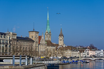 Fototapeta premium Scenic view of Limmat River with churches and the skyline of the old town of City of Zürich on a sunny winter day. Photo taken February 9th, 2023, Zurich, Switzerland.