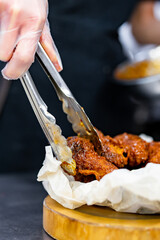woman chef cooking chicken wings in a sauce in the kitchen