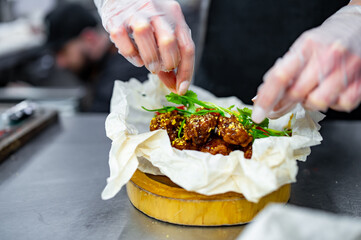 woman chef cooking chicken wings in a sauce in the kitchen