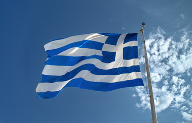 Greek flag waving against blue sky.
