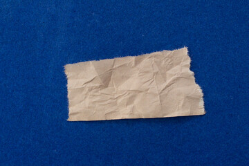 Crumpled paper on blue background. Ripped paper piece.
