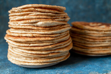 Flatbread lavash, chapati, naan, heap of tortilla on a blue background Homemade flatbread stacked.