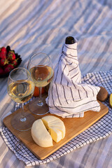 Top view flat lay bottle of white wine wrapped in a towel two glasses with wine sliced soft cheese, strawberries. Picnic in nature. Concept: outdoor recreation, summer mood, aesthetics