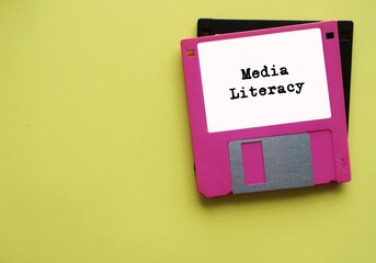 Pink floppy disk on copy space yellow background with text typed MEDIA LITERACY- concept of ability...