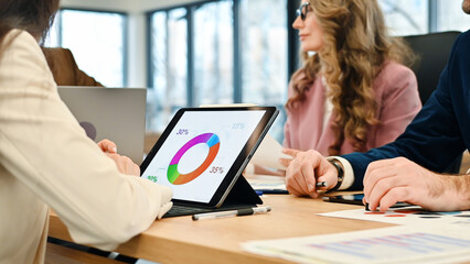 Business meeting in an office, workers discussing business affairs. Gadgets and papers with charts on the table