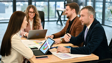 Business meeting in an office, workers discussing business affairs. Gadgets and papers with charts on the table