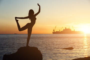 Silhouette of an acrobatic girl on the beach