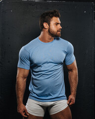 Bearded muscled man in blue shirt and white boxers looking to right side. Sexy fitness guy wearing...