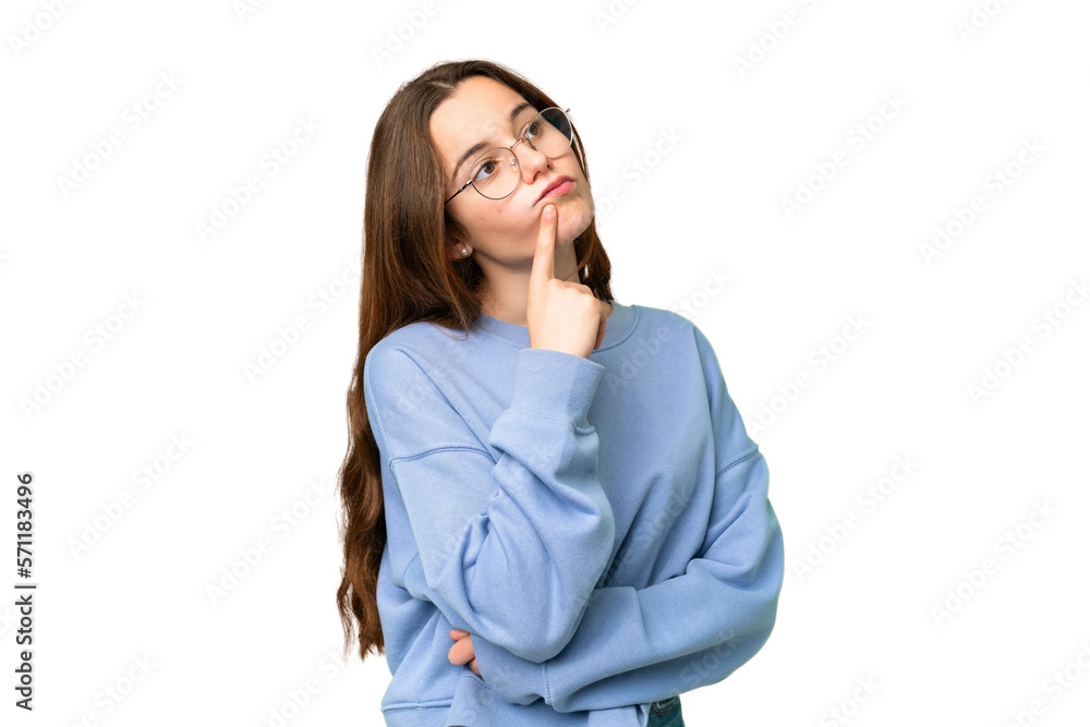 Wall mural Teenager girl over isolated chroma key background having doubts while looking up