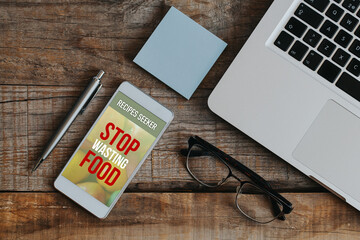 Stop wasting food app design on a mobile phone screen placed on a work desk. - 571183448