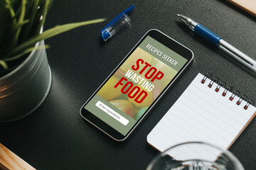 Mobile phone with Stop Wasting Food message and recipes seeker app in the screen, over a black table