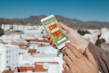 Man holding a mobile phone with Stop Wasting Food message and recipes seeker app in the screen.