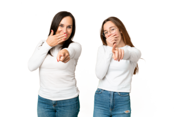 mother and daughter over isolated chroma key background pointing with finger at someone and laughing