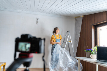 Camera on tripod shooting vlog, young woman renovating house, lifestyle concept