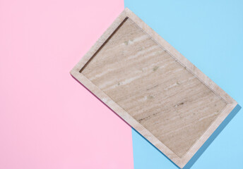 Empty beige rectangular marble plate on a blue pink background