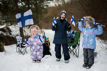 Three finnish children with Finland flags on a nice winter day. Nordic Scandinavian people.