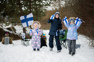 Three finnish children with Finland flags on a nice winter day. Nordic Scandinavian people.