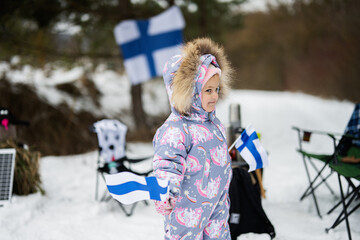 Finnish baby girl with Finland flags on a nice winter day. Nordic Scandinavian people.