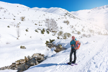 Fototapeta na wymiar woman in mountain gear looking the snowy river mountain