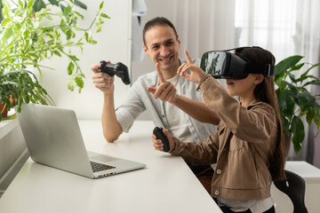 Little girl having fun time with her father using VR glasses at home for learning molecular...