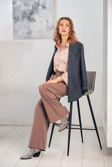 Women's business clothes in pink pastel colors. Palazzo trousers with a wide belt, silk blouse,...