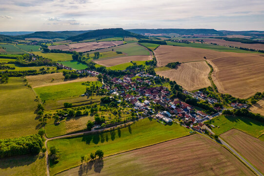 Aer ial view of a German village surrounded by meadows, farmland and forest in Germany.