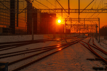 Jadący pociąg na torach kolejowych. Tory kolejowe zimą w zachodzącym słońcu. Odbicie na torach światła zachodzącego słońca