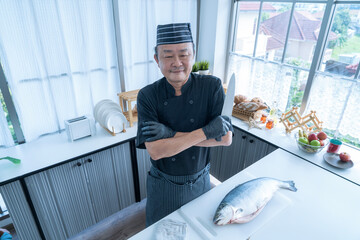 Happy japanese chef presenting a set of sashimi. The Asian man kitchen knife.