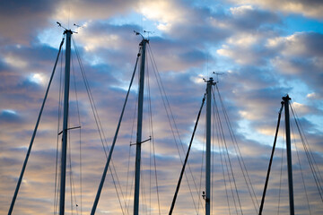 Flagpole of sailboats on a cloudy background by the sea.
