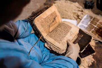 Ancient Qur'anic books displayed by the librarian wearing gloves