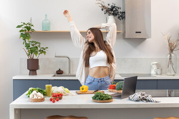An attractive woman smiles and dances while cooking a vegetarian dish. The concept of healthy eating