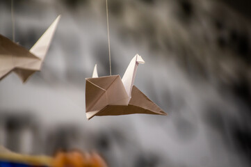 Japanese folded Origami cranes hanging on with strings. Hundreds handmade paper birds isolated with copy space. 1000 thousand crane sculpture topic. Symbol of peace, faith, health, wishes, hope