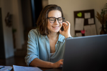 Happy creative young woman working on laptop at home. Remote work, small business and freelancing concept