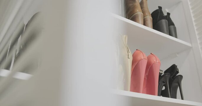 Look into the fashionista's shoe closet. Open louvered white wardrobe door with bright women's shoes with high heels.