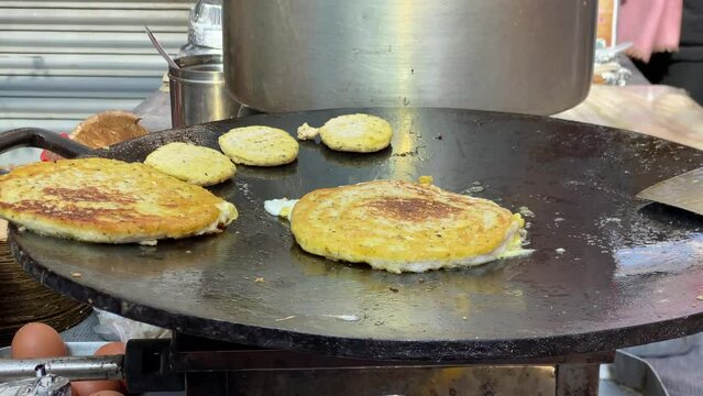 Some Newari bara frying on a skillet at a local market in Nepal.