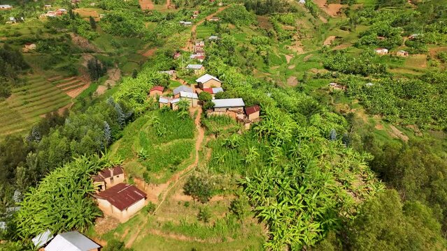 Drone flies over rural homes on a mountain side ridge in Rwanda.