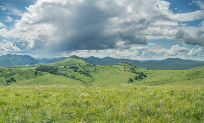 Fototapeta premium View of a summer day in the mountains, green meadows, mountain slopes and hills, countryside