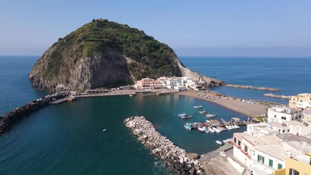 4k wide angle drone shot revealing the beautiful village of Sant Angelo located on the tropical island of Ischia in Italy during a beautiful morning with seagulls flying by and boats leaving port.