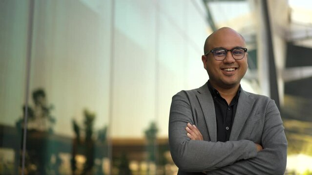 Confident smartly businessman manager smiling and arms crossed standing in a modern office. CEO, business owner proud of his success goals. Portrait Middle eastern businessman trader smiling.