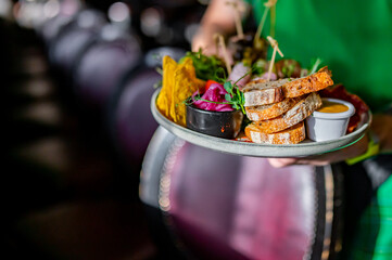 Waiter holda plate with tasty appetizers in restaurant