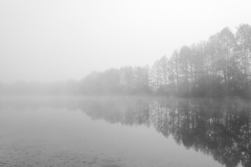 Germeringer See near Germering in Upper Bavaria. Landscape at the lake in the fog. Black and white shot. Foggy morning in nature.
