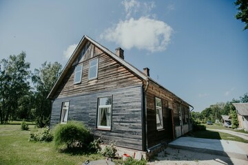 A large beautiful wooden two story abandoned farm house with peeling paint and broken windows in a rural summer countryside