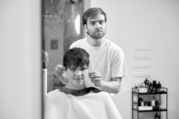 caucasian man getting haircut by professional male hairstylist