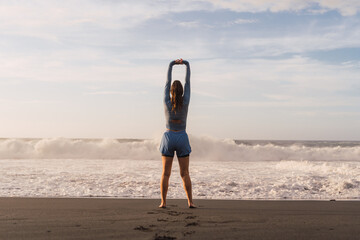 Fototapeta na wymiar sporty woman stretching her shoulders on the beach.
