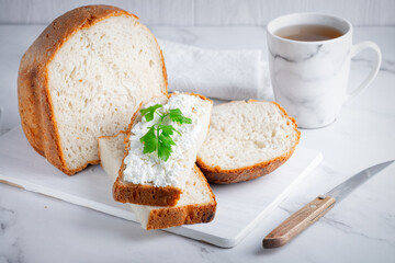 Home made bread on a wooden cutting board with curd cheese