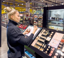 Woman buying make up at cosmetics section in store. choosing cosmetics, perfumes, creams and shampoos, Using tester.