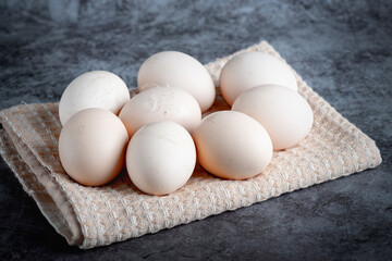 Chicken eggs on beige towel on grey background