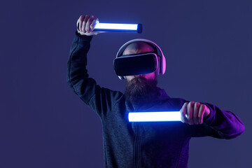 Young man in futuristic costume on dark background. Guy using VR helmet. Augmented reality, virtual...